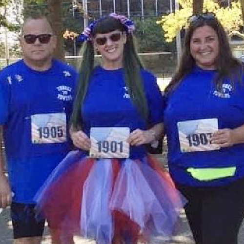 As she has done every year since 2012, Laurie Rudnick pulled up her striped socks and put on her Team Vigiano t-shirt, paired with her red, white, and blue tutu. But while the outfit was the same, this year, everything else would be different.  

Laurie would typically be preparing for the annual Tunnel to Towers 5k Run & Walk NYC, which takes runners through the then Brooklyn Battery Tunnel to Ground Zero to retrace FDNY Firefighter Stephen Siller’s final steps on 9/11. Each year, her participation honors her cousins, FDNY firefighter John Vigiano II and NYPD detective Joseph Vigiano, who also gave their lives that day.  The event typically draws more than 30,000 participants, but was cancelled this year due to citywide COVID-19 restrictions. Participants, like Laurie, were instead encouraged to take part in the Foundation’s newly launched Never Forget Virtual Challenge to honor the 9/11 fallen. And that’s exactly what she did. 

In the face of a global pandemic, Laurie was determined to safely get her family and friends together to keep the tradition alive. “Even if we walked around the block 20 times, I vowed that we will do every year, and that we would never forget,” Laurie said.  

With sunny and warm weather in the forecast, Laurie gathered her sister, parents, and friends in Eisenhower Park on Long Island and a teammate mapped out their own 5K route. 

One thing that was never in question was wearing her annual race outfit, red white and blue regalia from her head to her feet. “When I wear this in the race, it’s expected. At Eisenhower Park on a random Saturday, I was quite the spectacle,”Laurie said.  

The members of Team Vigiano weren’t the only ones in the park that morning, there was also a platoon of Marines. “I said look, the Marines are here! It feels like the real run. As we made our way back I heard someone yell my name, and it happened to be my cousin Joe. He was with his platoon doing drills that day,” said Laurie.

Joe, who had run with the team in 2019, recognized his cousin’s outfit and called out to her, making the event even more of a family affair. The signature outfit also helped Laurie share her story with strangers in the park who asked her questions. One person even took a picture. “There is a photo of me with a stranger out there somewhere,” Laurie laughed. 

For Laurie, these random encounters are a chance to tell stories about her cousins and the Tunnel to Towers Foundation, which is helping Gold Star and fallen first responder families and catastrophically injured veterans across the country. 

“They have been gone for 19 years. I have a million stories, but that’s all I have left. It’s good to use our cousins’ names and their stories to do good for the people that are still here.”

The Tunnel to Towers Foundation would like to thank Laurie, her family and friends for keeping the promise America made 19 years ago, to Never Forget. You can also help to keep that promise and do good by donating to Tunnel to Towers at t2t.org.
